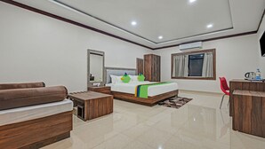 Habitació d'hotel moderna amb un llit, un sofà, un escriptori i una cadira vermella.