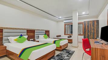 A hotel room with two beds, a desk, a chair, a TV, and a window with curtains.