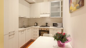 A compact kitchen with white cabinets, a gas stove, a microwave, and a sink. - Appartamento Vaticano per 6 persone (Rome)