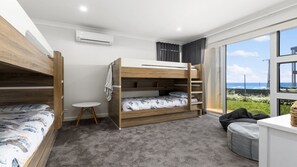 A modern bedroom with bunk beds, a small round table, and a view of the ocean.
