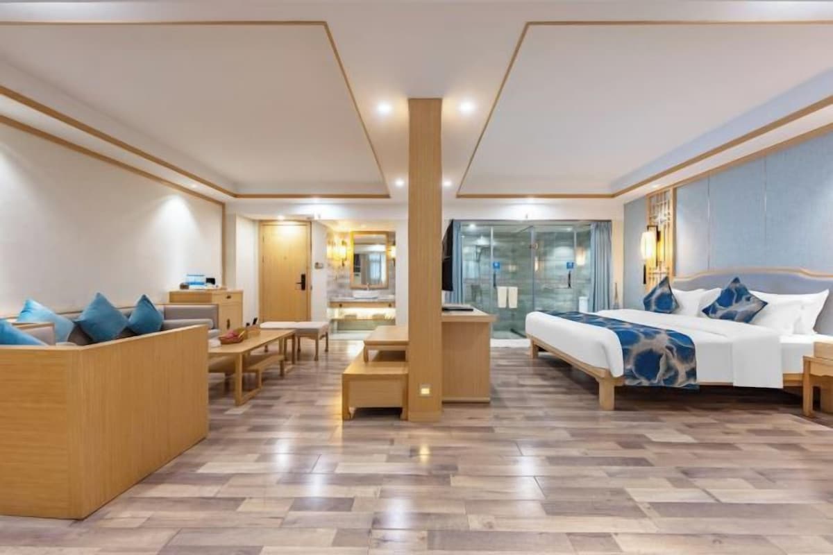Una habitación de hotel moderna con una cama grande, zona de estar y vistas a la ciudad.