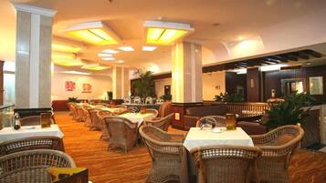 A restaurant with wicker furniture, tables, and a warm ambiance.