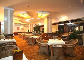 Un restaurante con mobiliario de mimbre, mesas y un ambiente cálido.