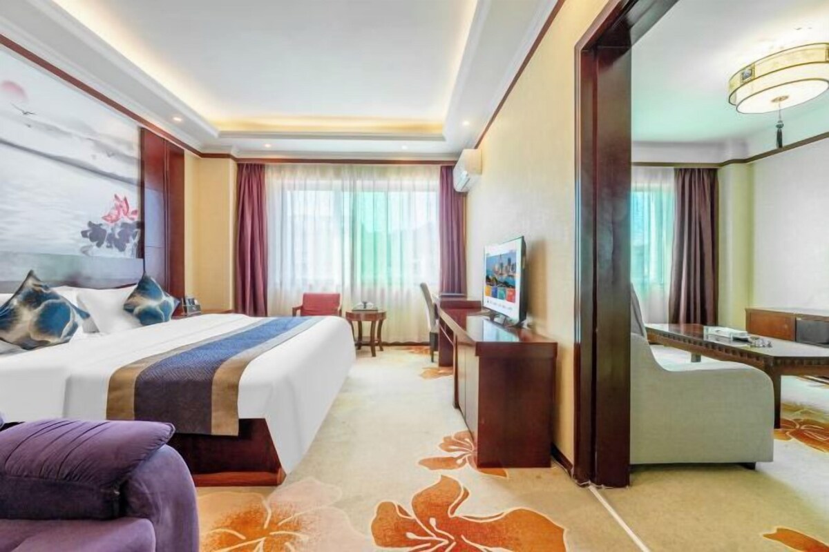 A hotel room with a bed, desk, chair, and a television.