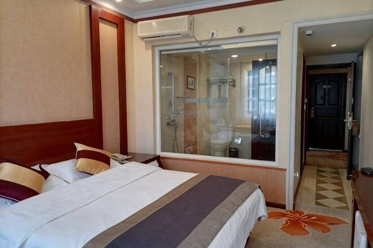 Ein Hotelzimmer mit einem großen Bett, einer Duschkabine aus Glas und Blick ins Freie.