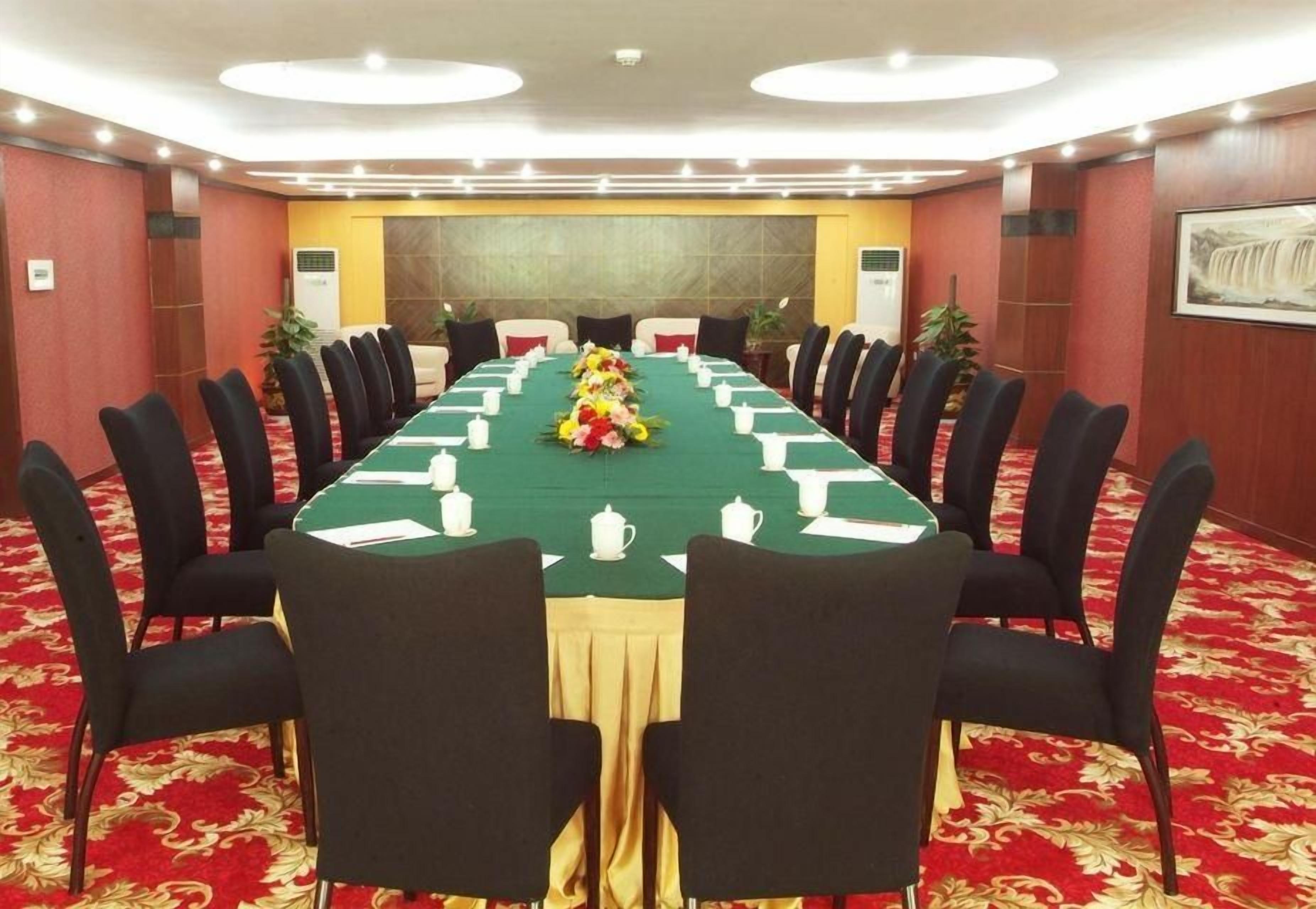 A conference room with a long table, chairs, and a floral centerpiece.