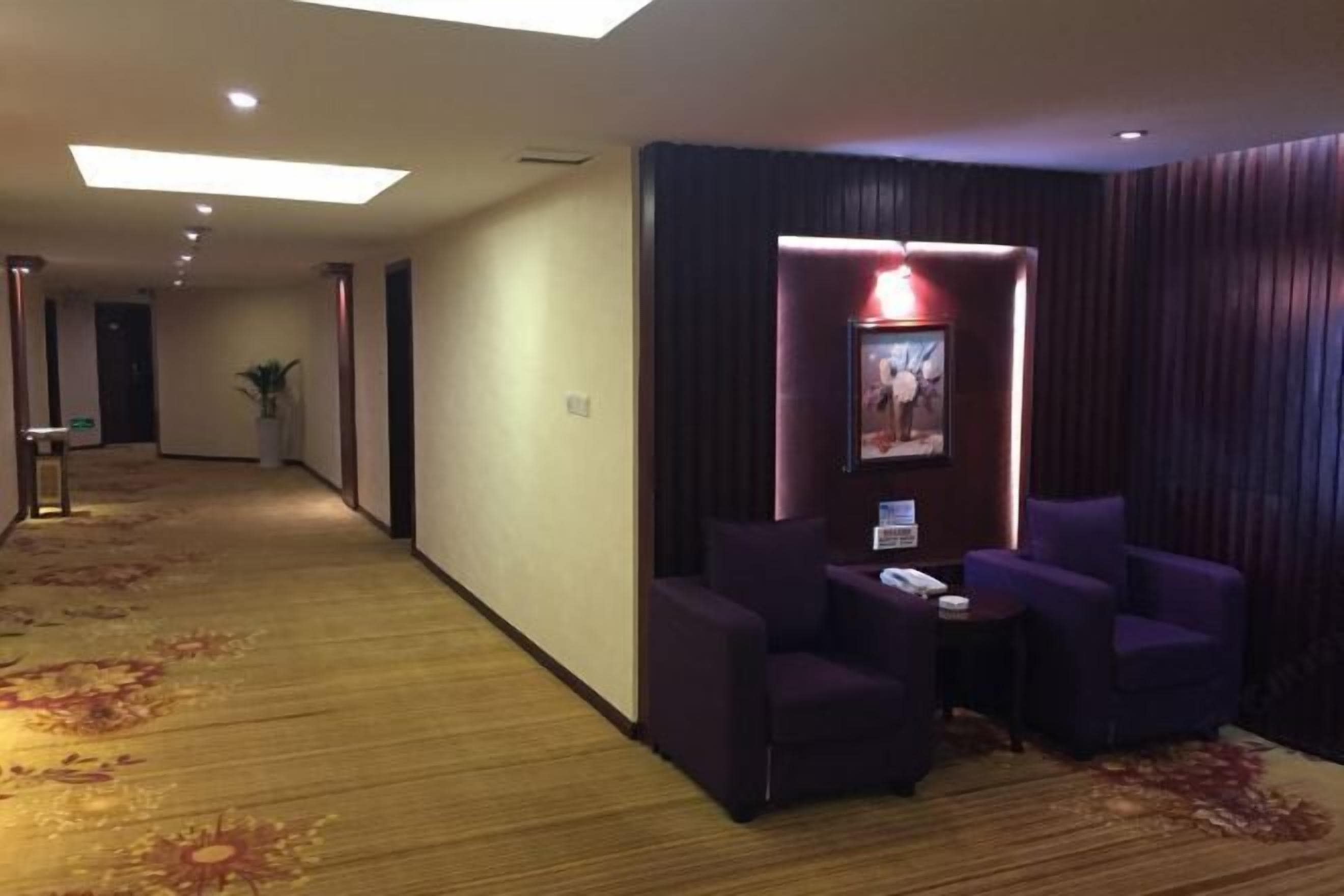 A hotel lobby with a carpeted floor, a reception desk, and purple seating area.