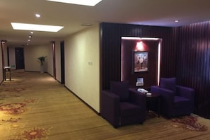 A hotel lobby with a carpeted floor, a reception desk, and purple seating area. - Jinmeng (Wenshan City)