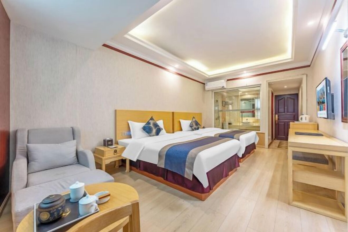 A hotel room with a bed, a sofa, a desk, and a small table with items on it.