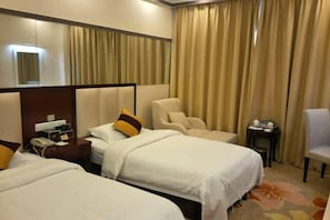 Habitación de hotel con dos camas, una silla, una mesita y un espejo.