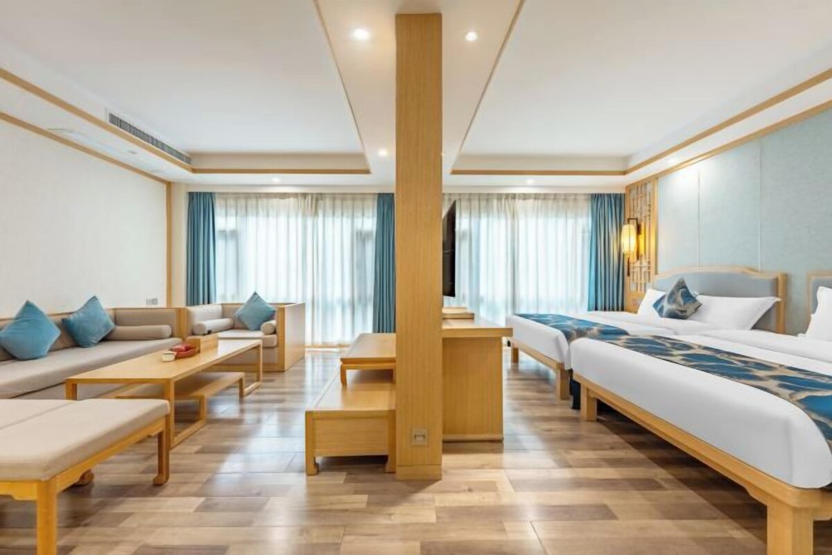 A hotel room with a sofa, a bed, a desk, and a chair.