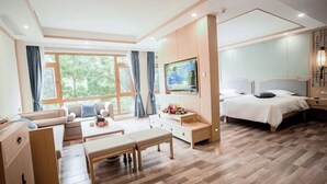 A modern hotel room with a large bed, a sofa, a dining table, and a TV. - Jinmeng Hotel (Wenshan City)