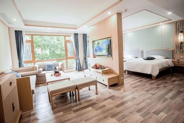 Una habitación de hotel moderna con una cama grande, un sofá, una mesa de comedor y un televisor.