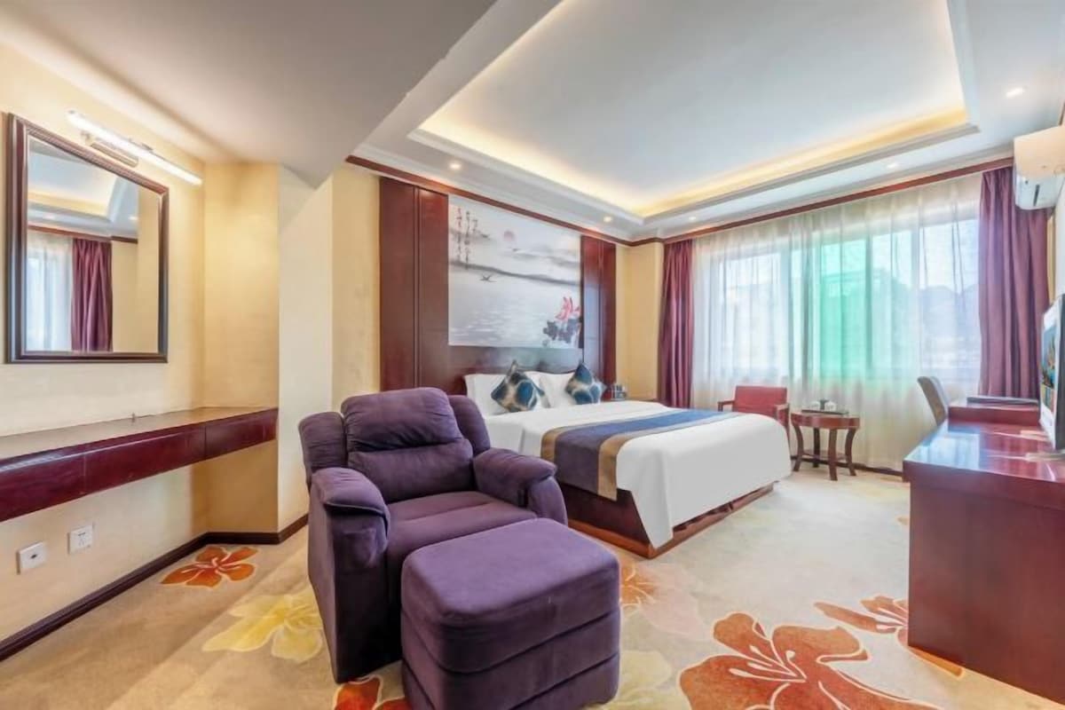 Una habitación de hotel con cama, sofá, escritorio y un ventanal grande.