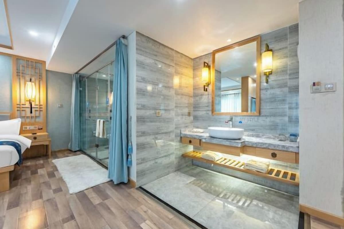 Un baño moderno con cabina de ducha de vidrio, un espejo grande y un tocador de madera.