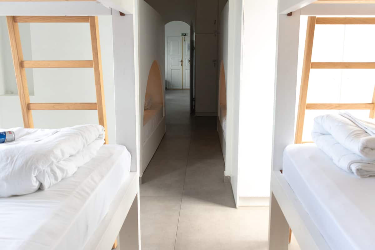 A corridor with bunk beds on either side, leading to a door at the end.