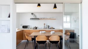 A modern kitchen with a wooden table, four chairs, a microwave, and a coffee maker.