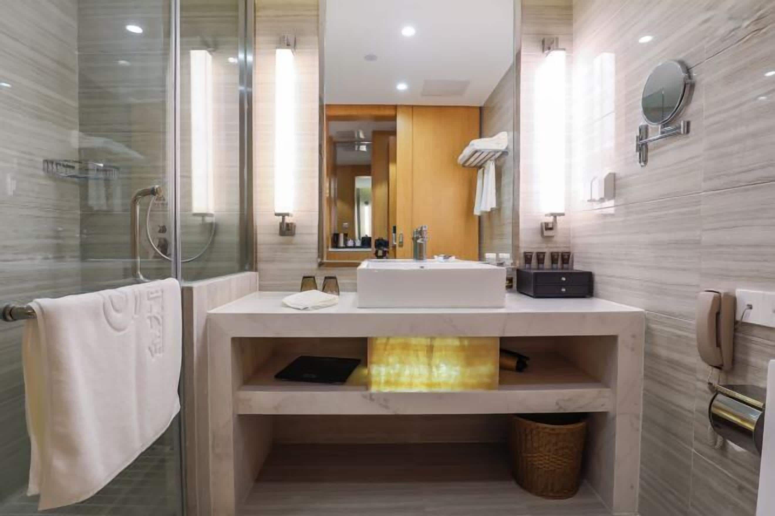 A modern bathroom with a glass shower enclosure, a vanity with a sink, and a mirror.