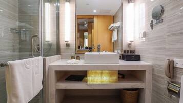 A modern bathroom with a glass shower enclosure, a vanity with a sink, and a mirror.