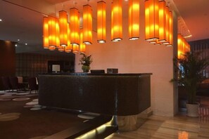 A reception area with a curved reception desk, multiple pendant lights, and a potted plant. - Golden Sun Hotel (Lai'an)