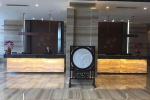A reception area with two counters, a central decorative piece, and a modern interior design. - Golden Sun Hotel (Lai'an)