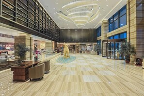 Eine geräumige Lobby mit hoher Decke, einer zentralen Skulptur und einem Empfangsbereich.