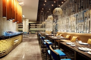 A restaurant with long tables, blue chairs, and hanging light fixtures. - Golden Sun Hotel (Lai'an)