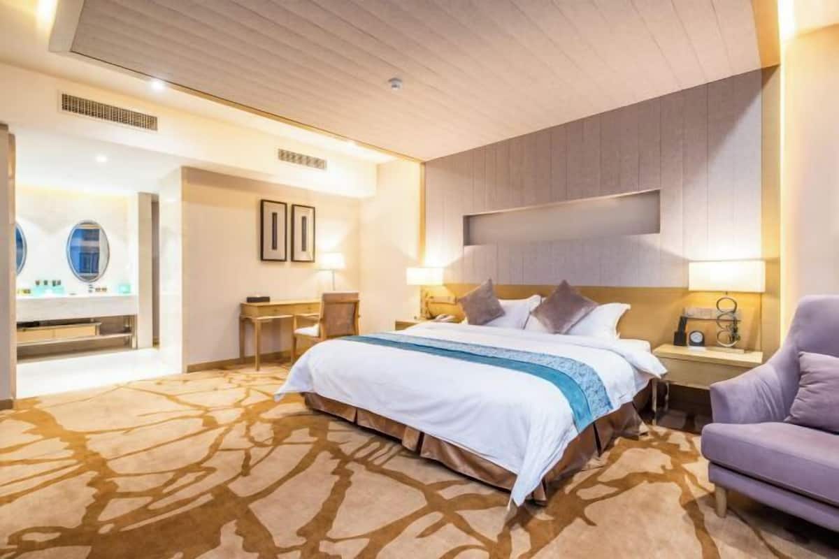 Hotellihuone, jossa on suuri sänky, työpöytä, tuoli ja sohva.
