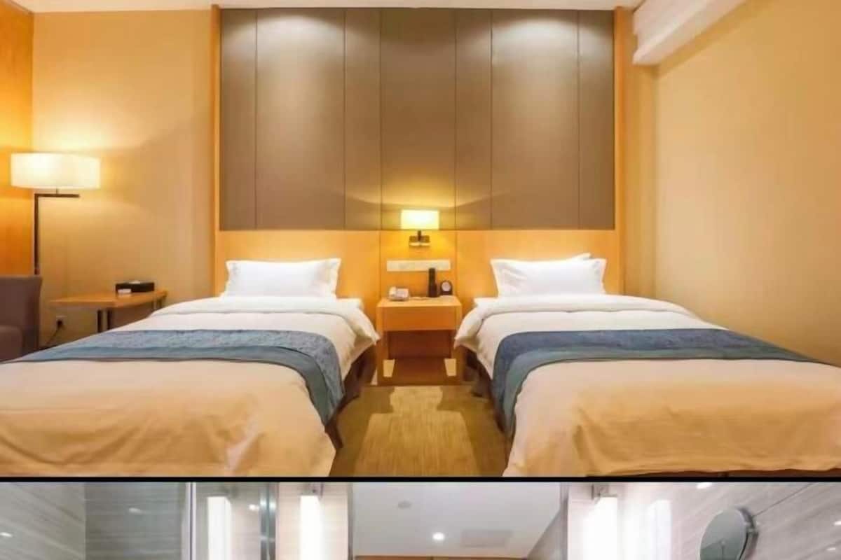 Hotellihuone, jossa on kaksi sänkyä, yöpöytä, lamppu ja vaatekaappi.