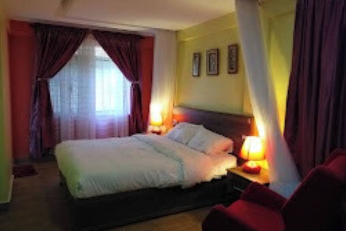 A bedroom with a bed, two bedside lamps, a nightstand, and a chair.
