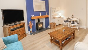 A living room with a TV, fireplace, dining table, and chairs. - Elm Cottage (Bishop Auckland)