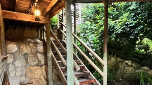 Un escalier en bois, doté de rampes en métal, mène à un mur de pierre.