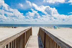 A wooden boardwalk leading to a sandy beach with a clear blue sky and scattered clouds. - Lagoon Tower 302, 3/3 | Private Beach Access (Gulf Shores)