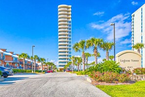 Un hotel moderno con una torre destacada, un césped cuidado y un cielo despejado.