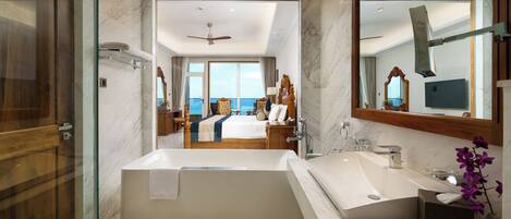 A modern bathroom with a large bathtub, a double sink, and a large mirror.
