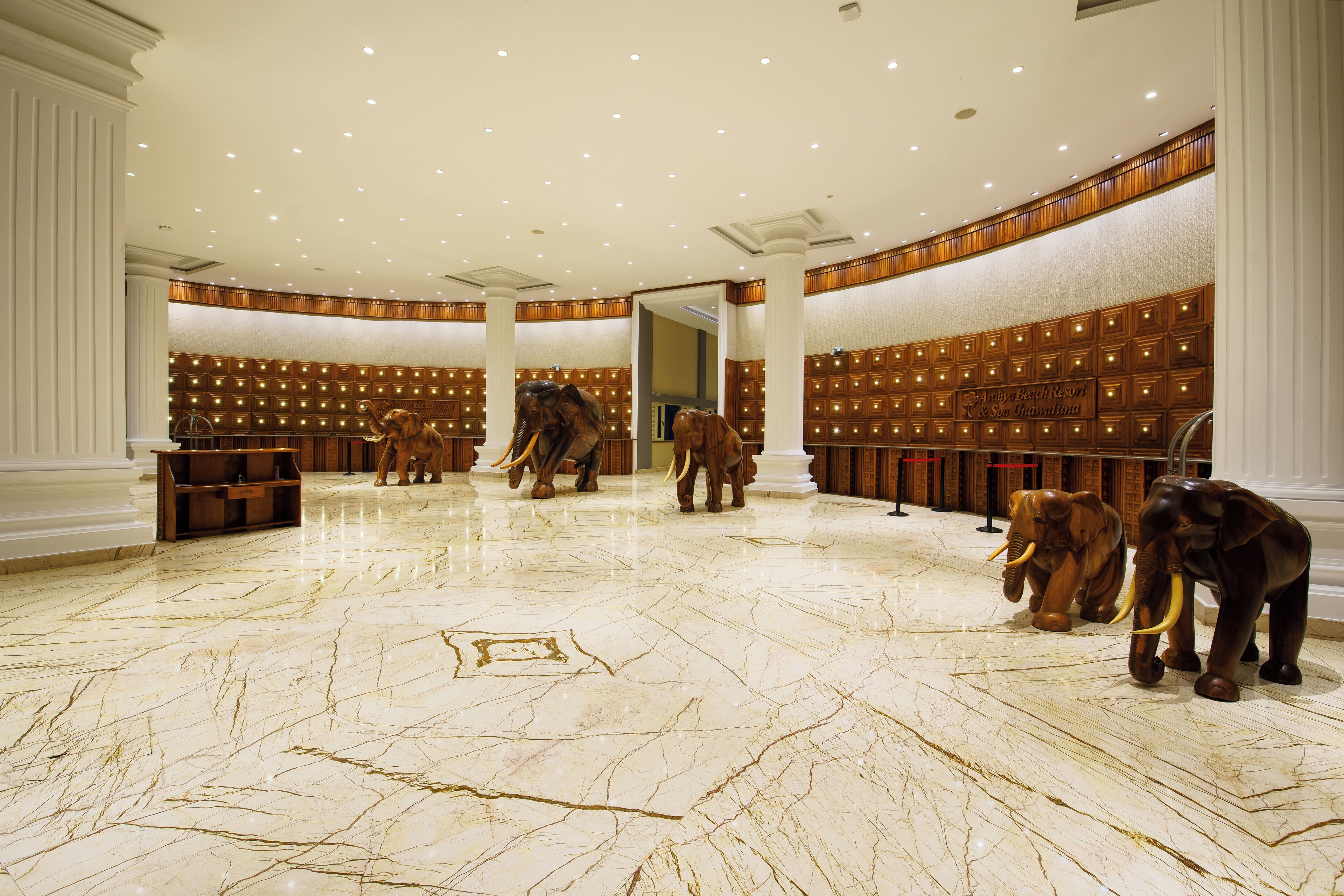 Eine geräumige Lobby mit Marmorböden, Holzvertäfelung und einer Reihe von Elefantenstatuen.