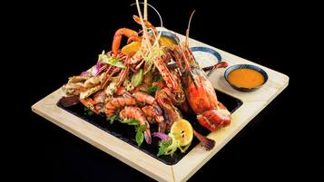 Un piatto di pesce con diversi tipi di crostacei e guarnizioni, accompagnato da una ciotola di salsa.
