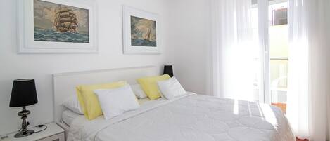 Un dormitorio con cama, mesita de noche, lámpara y dos cuadros en la pared.