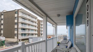 Ein Balkon mit Korbstühlen und einem kleinen Tisch, mit Blick auf ein Gebäude mit mehreren Balkonen.