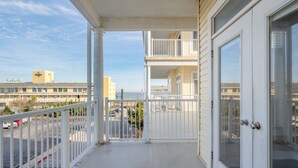 A balcony with a view of a parking lot and buildings in the background. - Stunning ocean block condo with 5 bedrooms and 4 and 1/2 baths! (Ocean City)