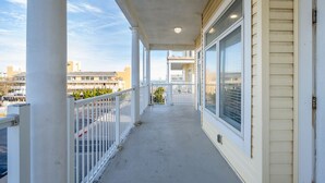 A balcony with a concrete floor, white railings, and large windows. - Stunning ocean block condo with 5 bedrooms and 4 and 1/2 baths! (Ocean City)