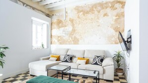 A living room with a white sofa, a glass coffee table, and a checkered floor.