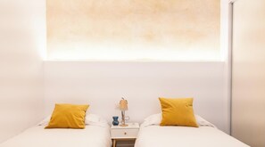 Un lit double avec deux oreillers, une table de chevet avec une lampe et un luminaire fixé au mur.