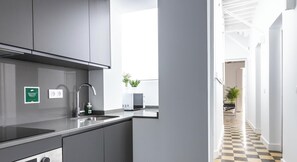 A modern kitchen with grey cabinets, a stainless steel sink, and a microwave.