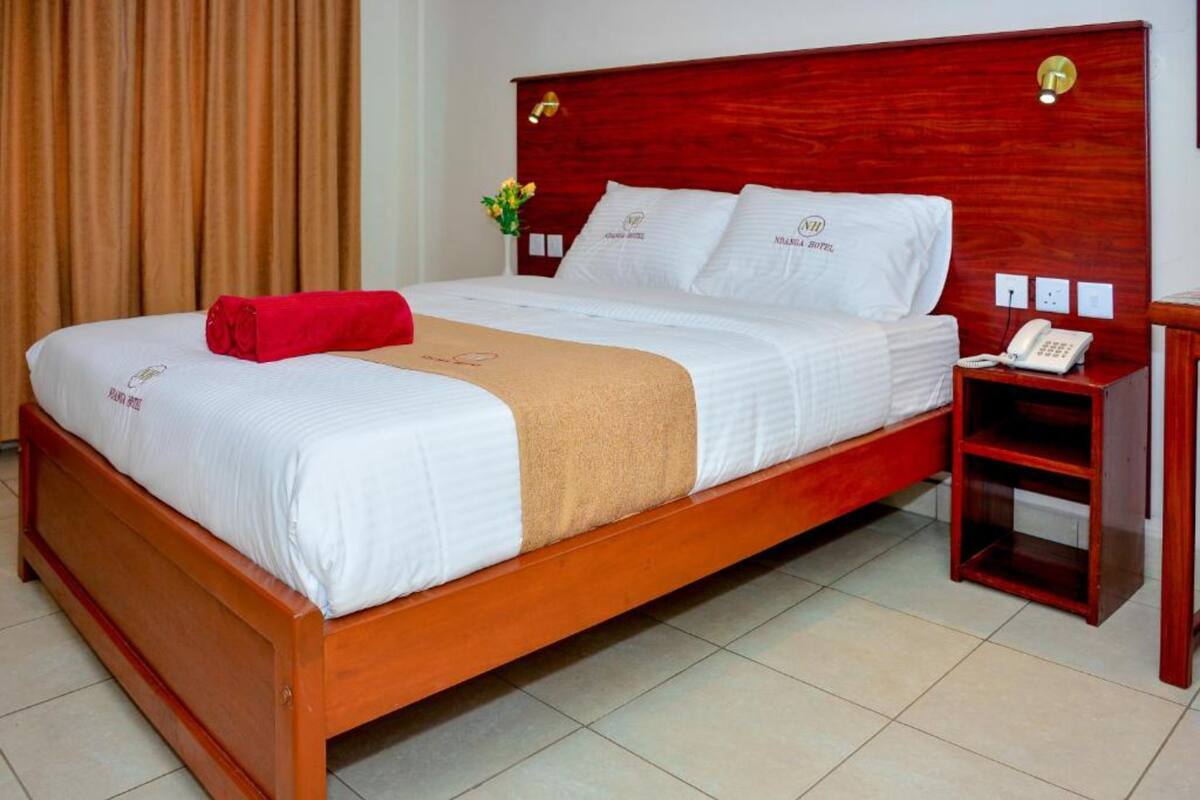 A neatly made bed with a red towel, white bedding, and a wooden headboard.