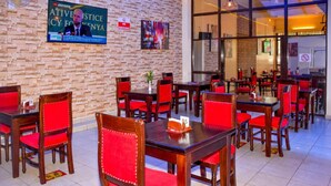 A restaurant with brick walls, red chairs, and tables. - Ndanga International (Ruiru)