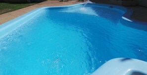 Une piscine à l’eau d’un bleu limpide, avec un bord incurvé.