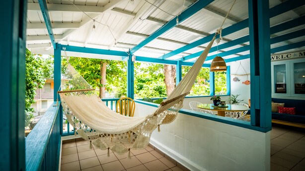 A hammock hanging from a ceiling in a room with blue and white walls, a tiled floor, and a view of greenery outside. - Aguasalá Beach House, Puerto Nuevo Beach (Vega Baja)