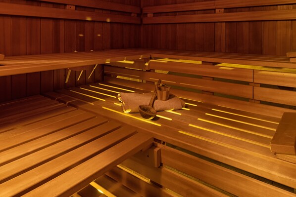 A sauna with wooden benches and benches, and a small wooden structure in the center.