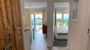 A modern interior with a wooden door, a round rug, a bed, and a balcony with a view. - Albufeira Beach Apartment (Guia)